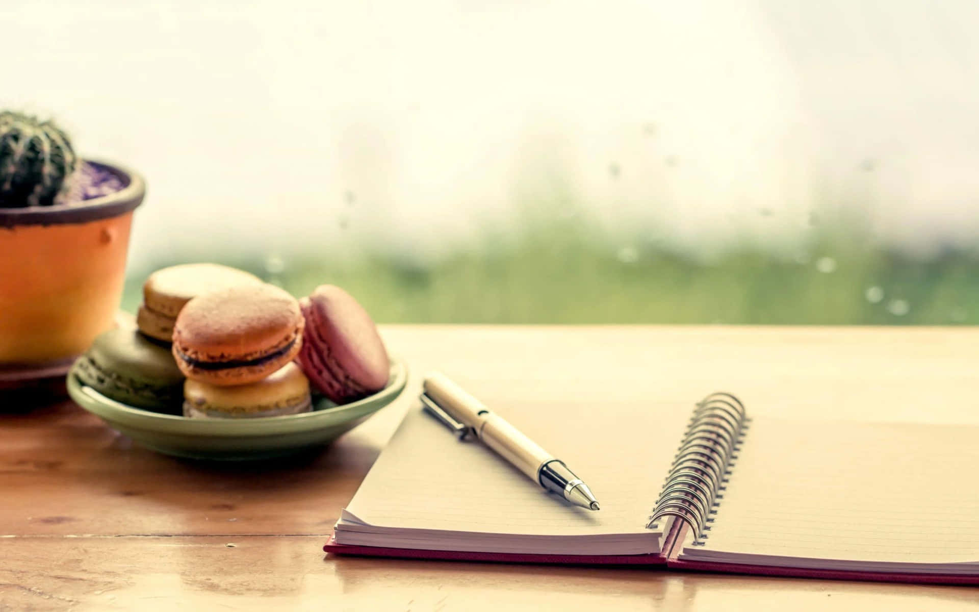 A Notebook, Pen, And Macarons On A Table