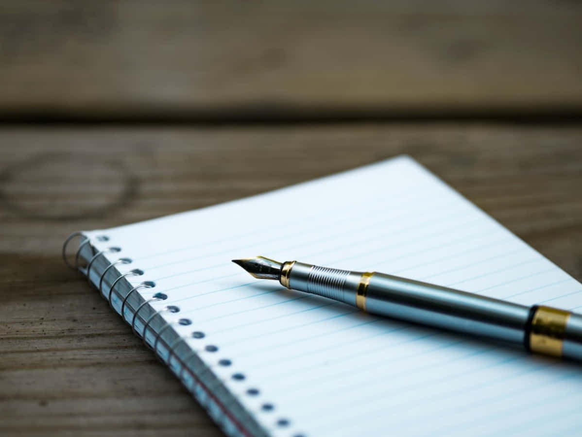 A Pen On A Notebook On A Wooden Table