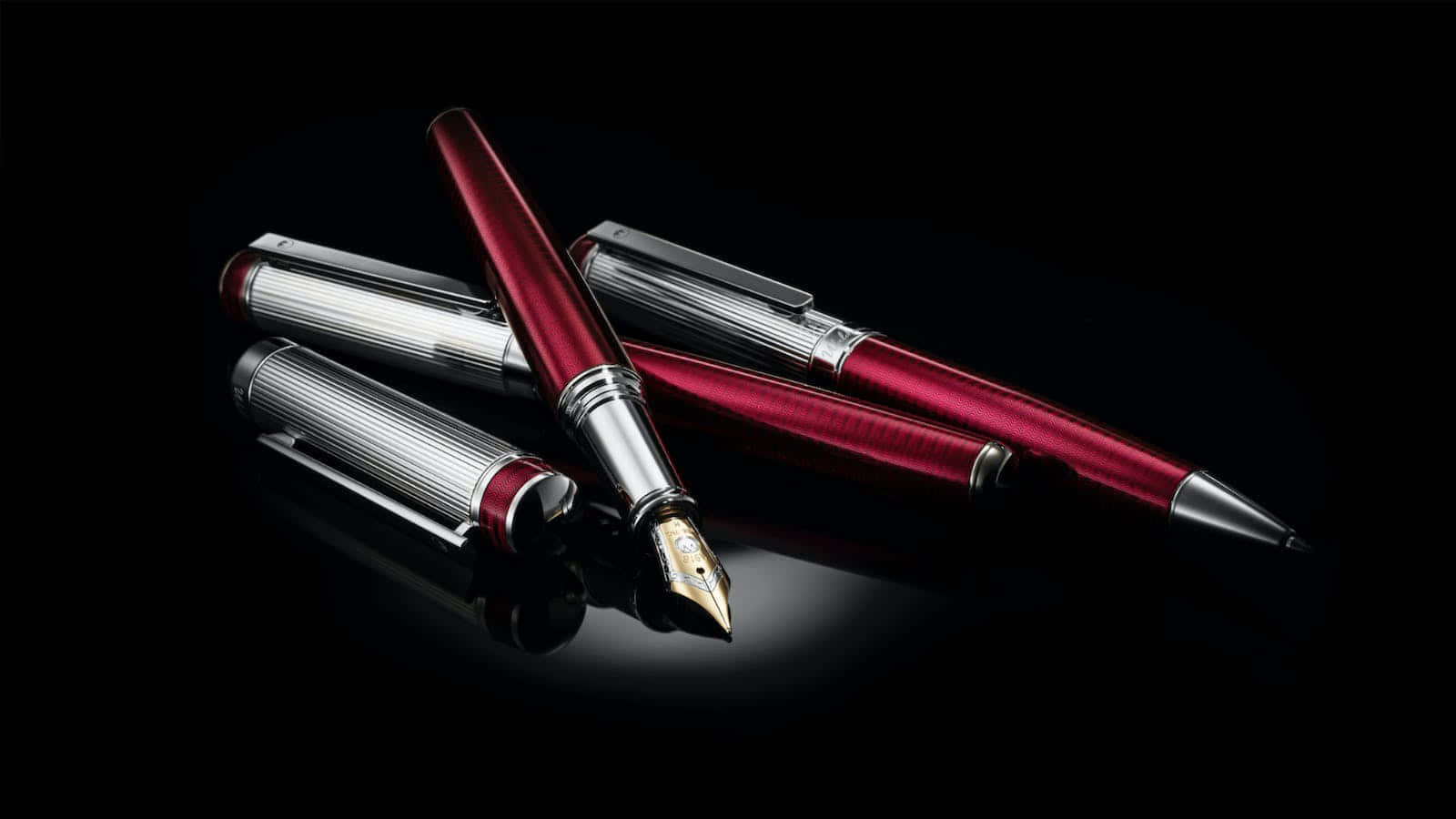 A Red Fountain Pen And A Silver Pen On A Black Surface