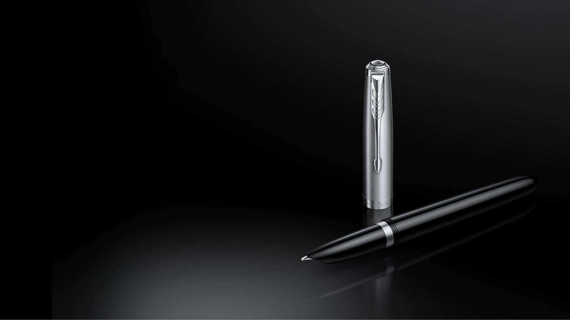 A Pen With A Black And Silver Finish On A Black Surface