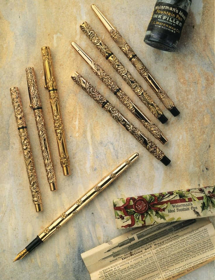 A Collection Of Gold Pens And A Book