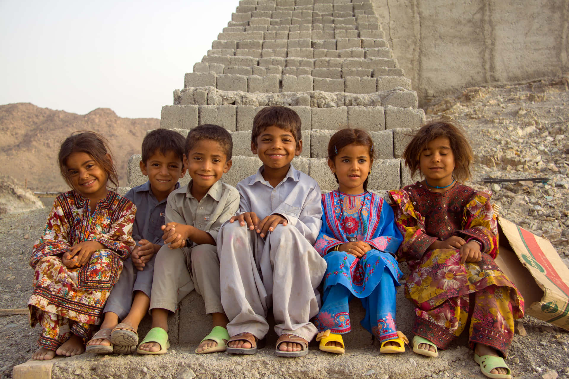 A Group Of Children Sitting On A Pile Of Bricks