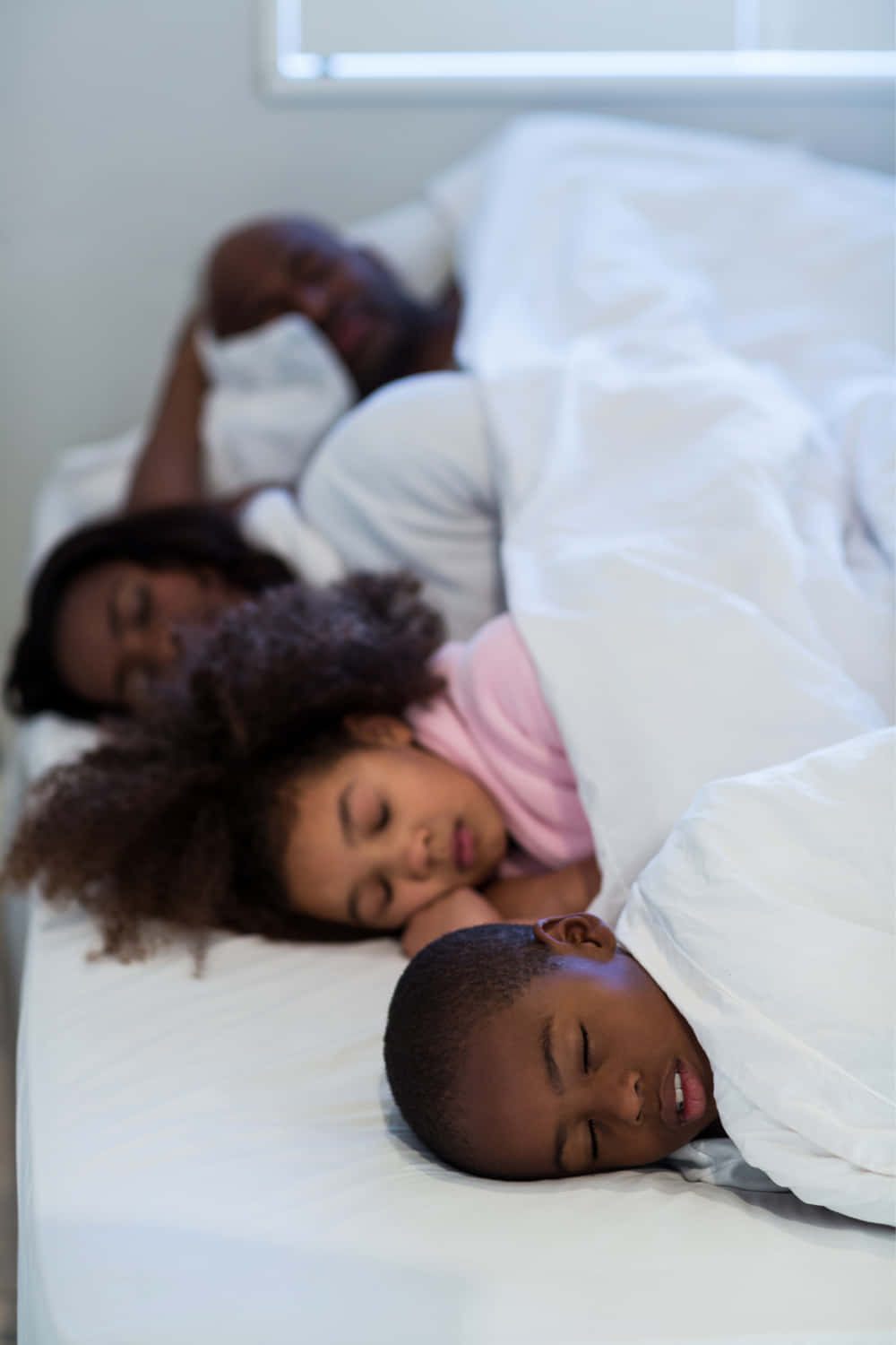 A Family Sleeping In Bed