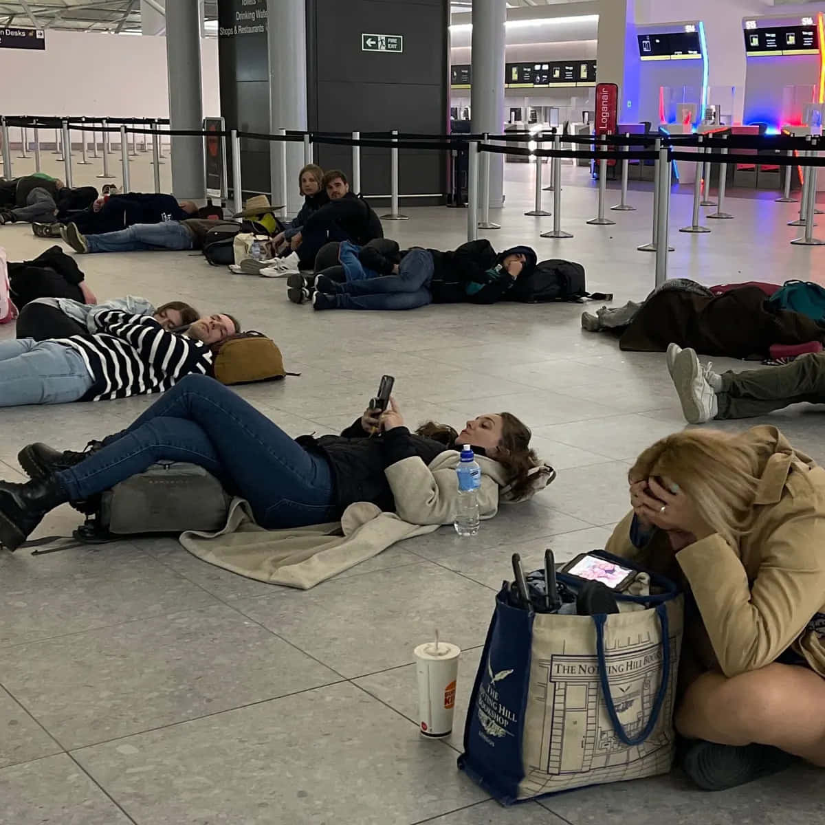 Laspersonas Están Acostadas En El Suelo En Un Aeropuerto.