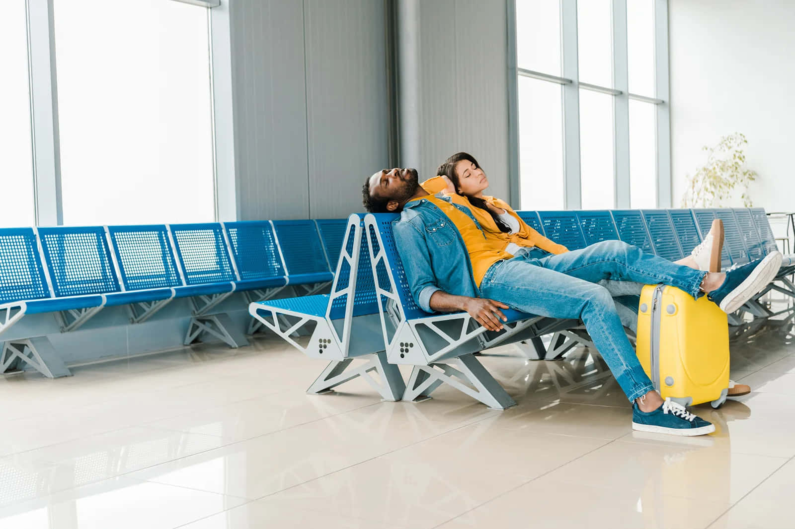 Two People Sitting On A Bench In An Airport