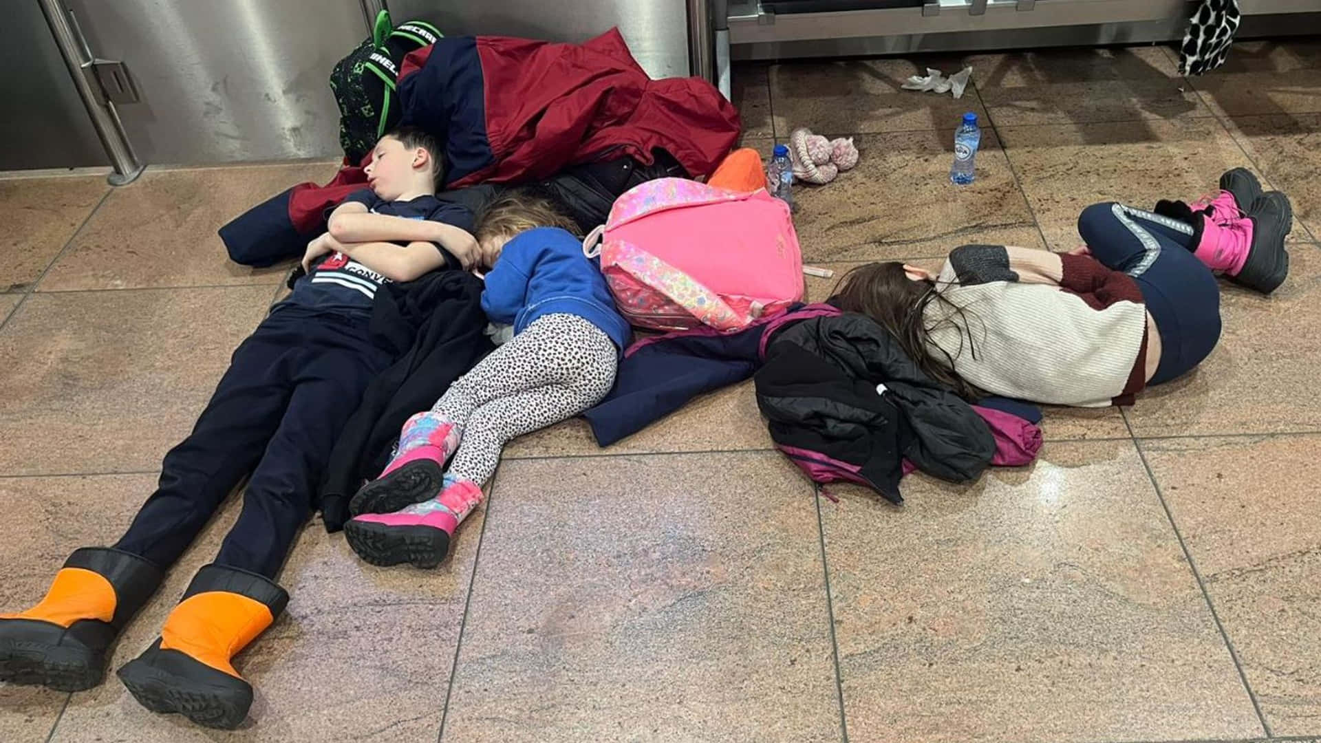 A Group Of Children Are Sleeping On The Floor Of An Airport