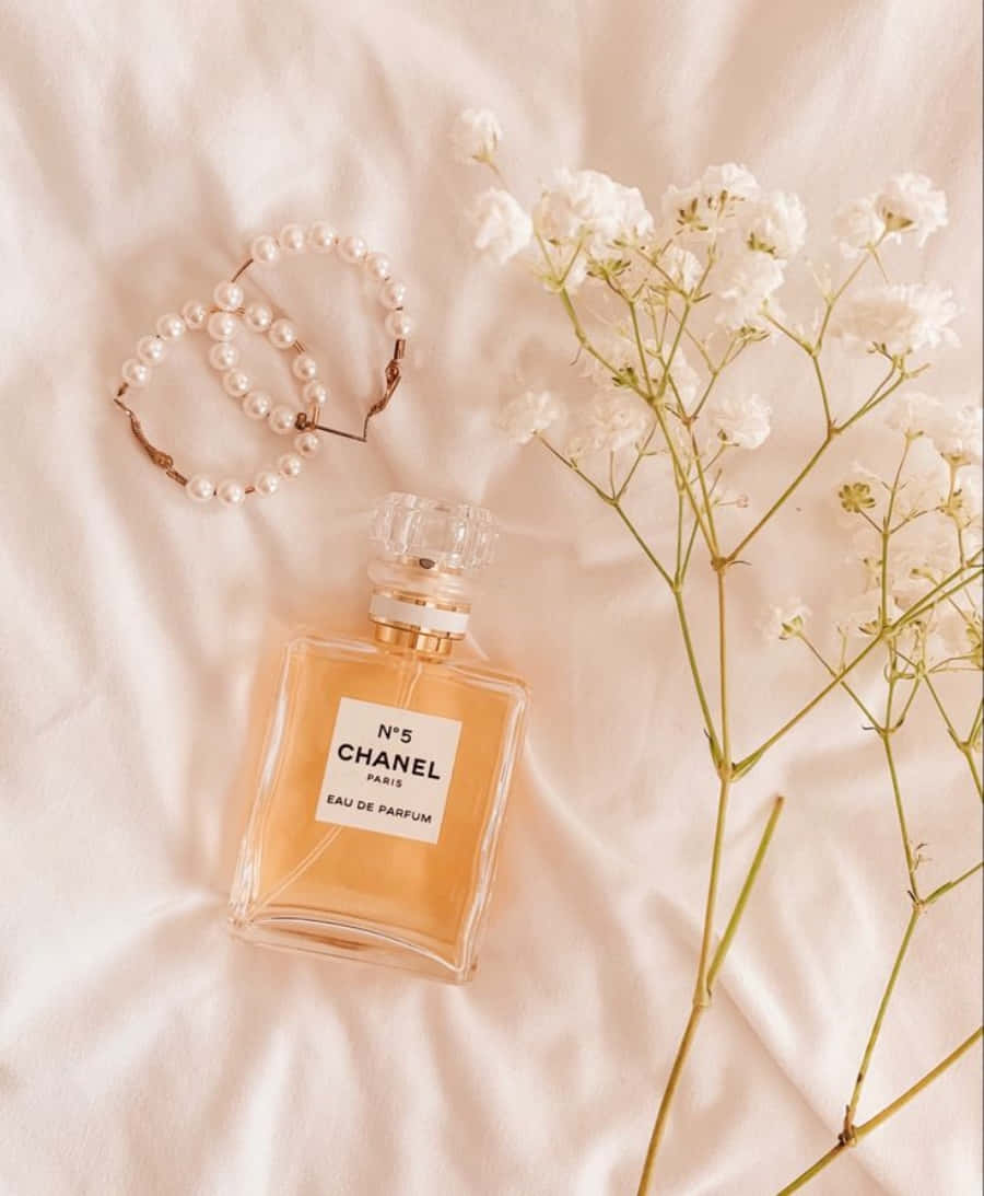 Download Chanel Perfume On A White Bed With Flowers