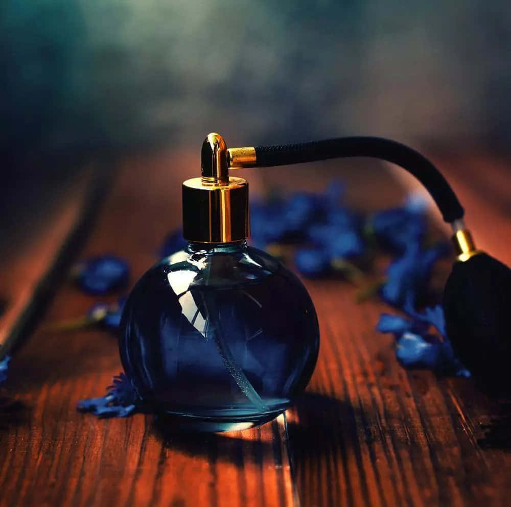 A Blue Perfume Bottle With Blue Flowers On A Wooden Table