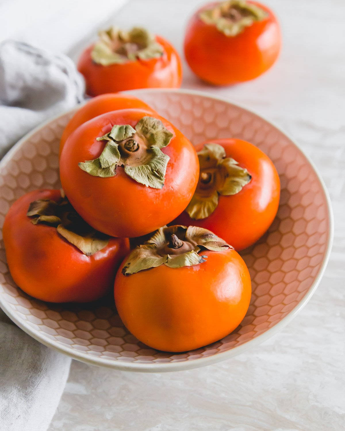 Caption: Fresh Persimmons in a Porcelain Bowl on Rustic Table Wallpaper