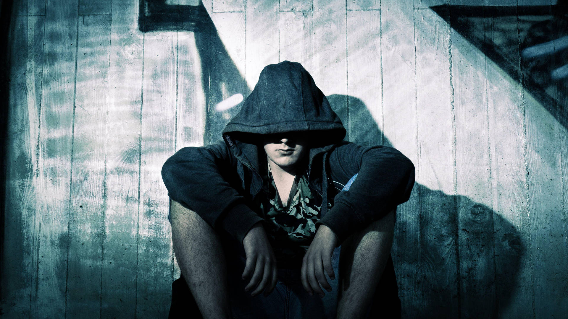 Person In Hoodie Leaning Against Wall Wallpaper