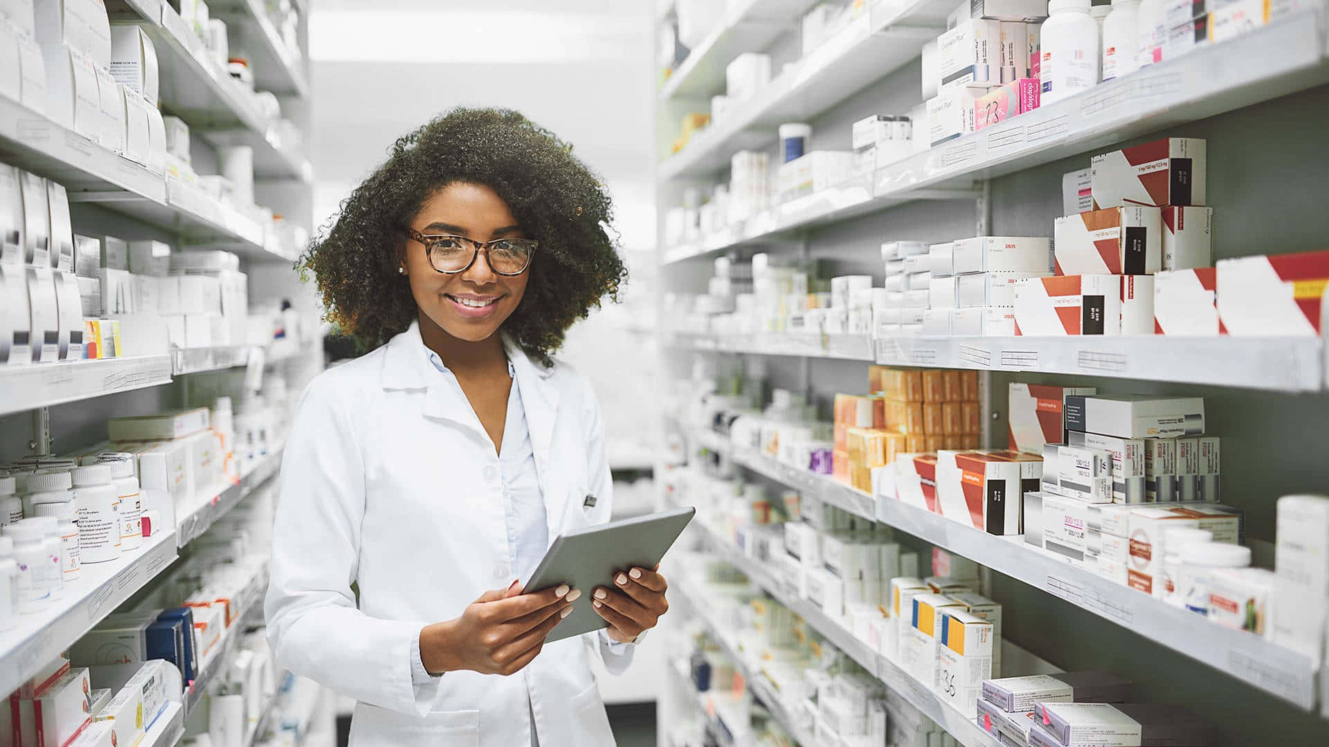 A Female Pharmacist In A Pharmacy Holding A Tablet