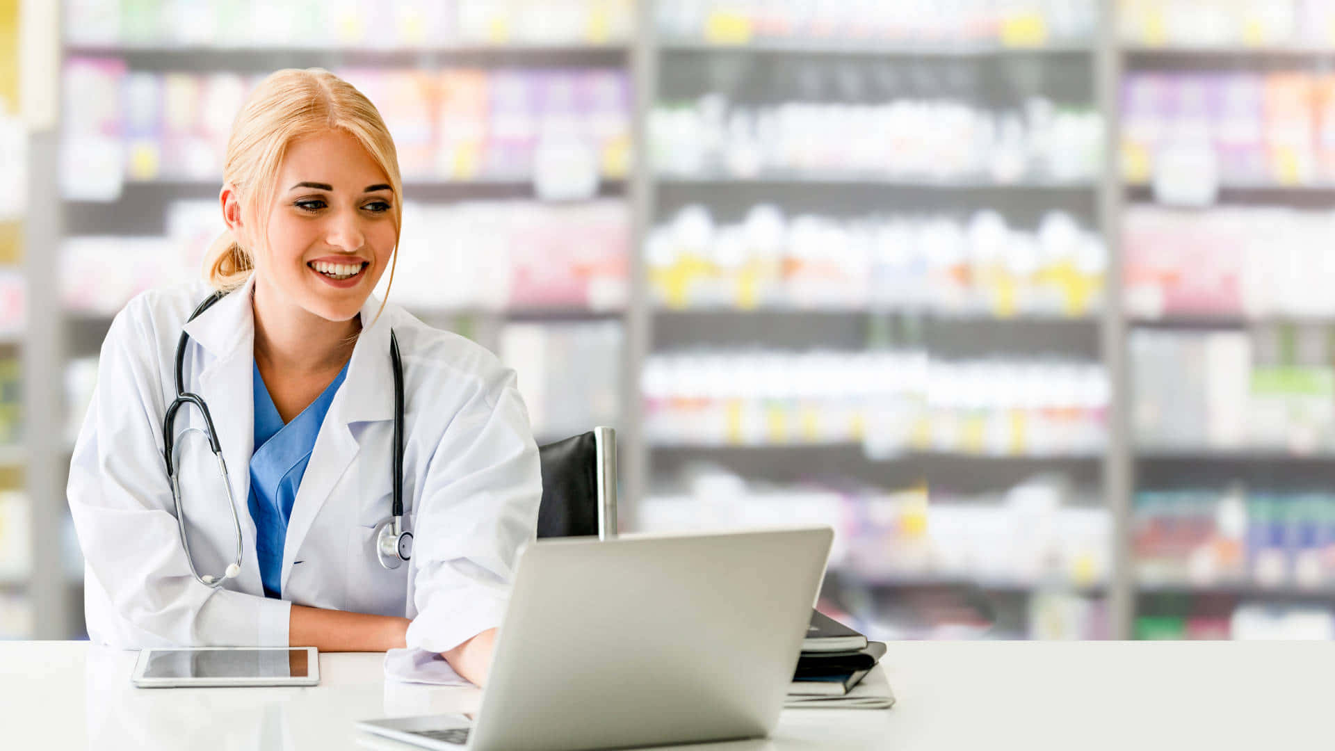 A Female Pharmacist Is Sitting At A Desk With A Laptop