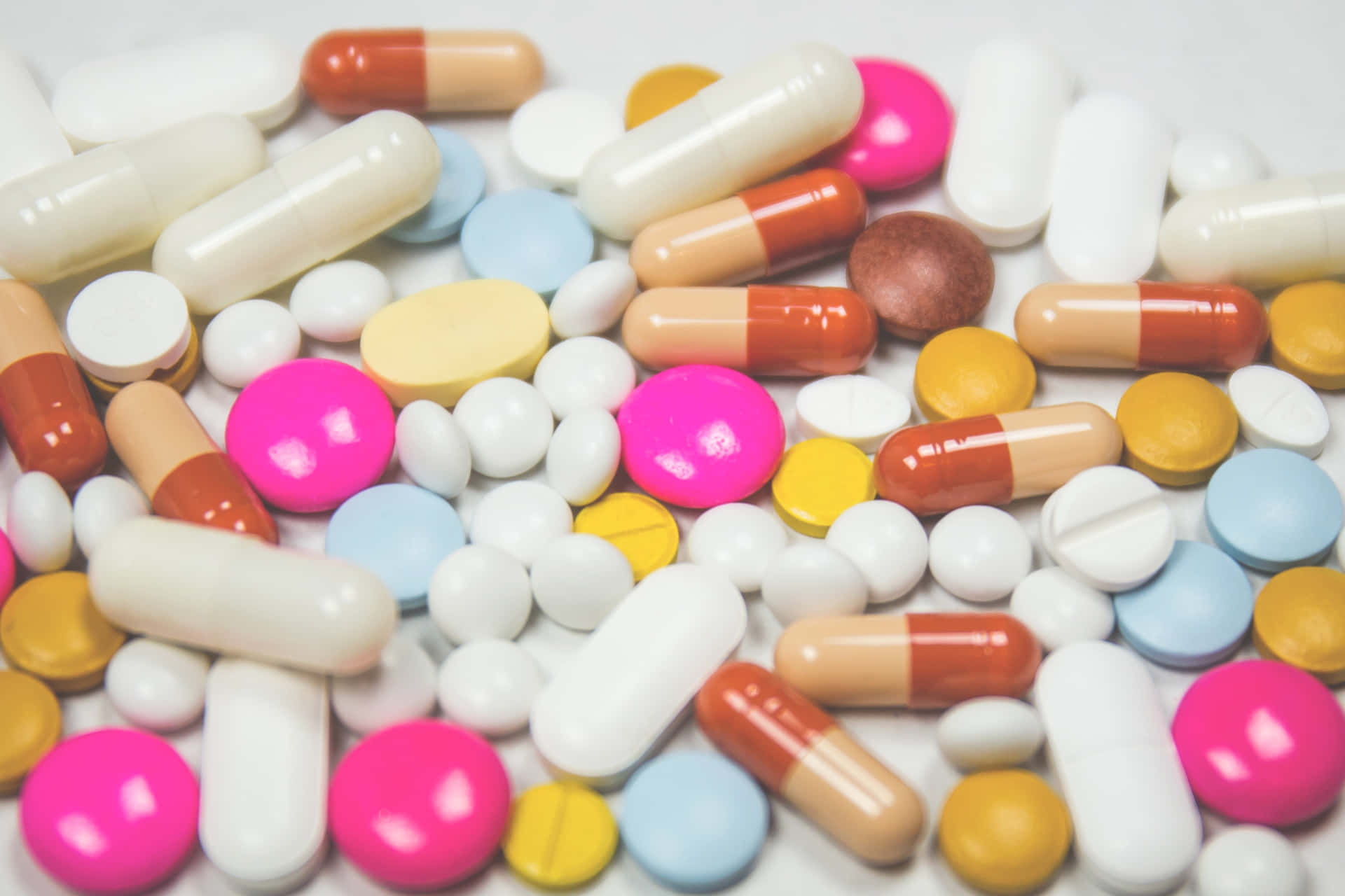 A Pile Of Pills And Capsules On A White Surface