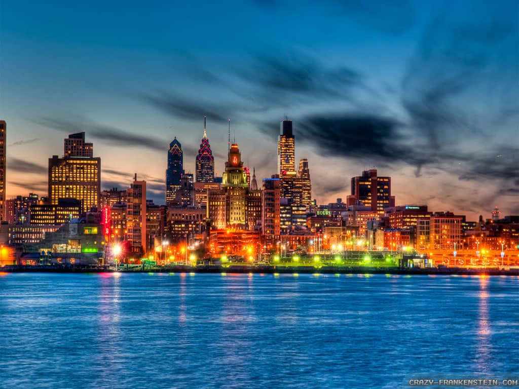 A City Skyline At Night With Lights On The Water Wallpaper