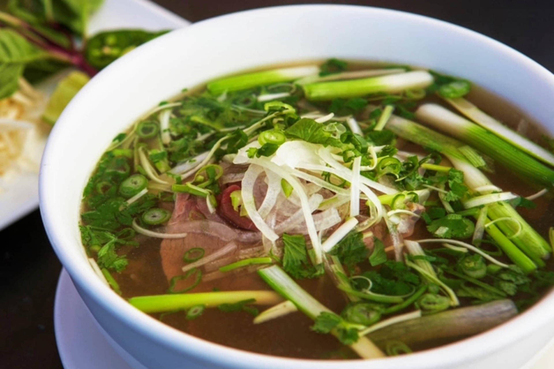 A Delicious Bowl of Beef Pho with Spring Onions Wallpaper
