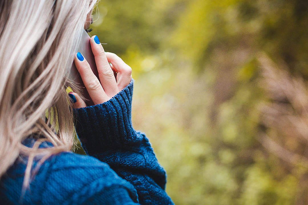 Kvinde ved telefonopkald med blå sweater og grå bukser Wallpaper