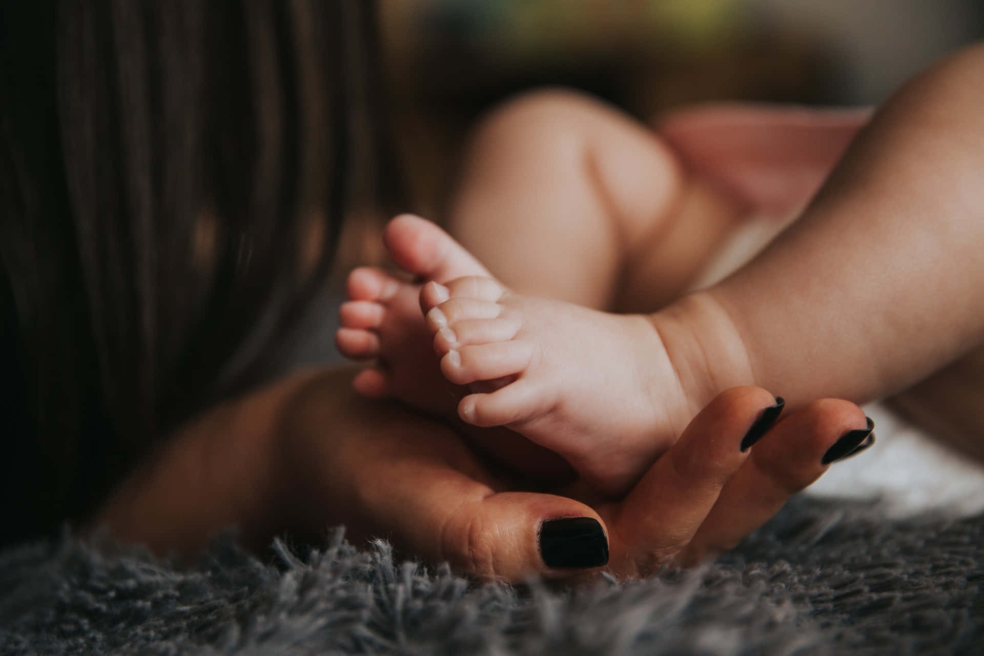 Photo Of A Mother's Hand Holding The Tangible Feet Of A Baby Wallpaper