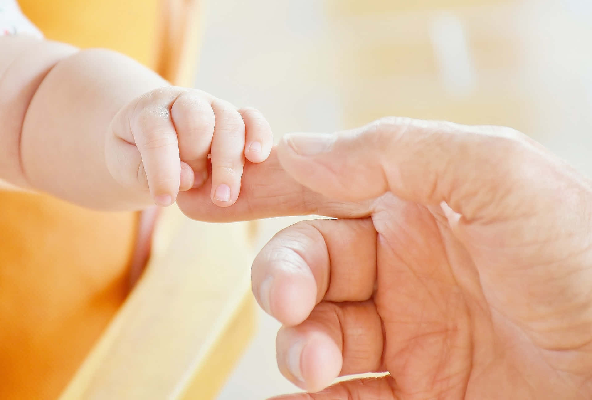 Photo Of Tangible Touching Of Hands Of A Baby And Older Person Wallpaper