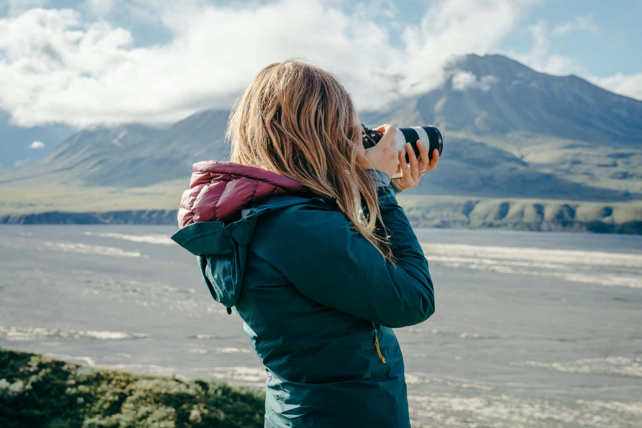 A Woman Taking A Picture Of Mountains And Water