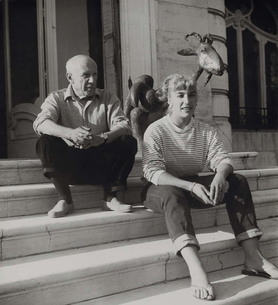 A Man And Woman Sitting On Steps With A Bird