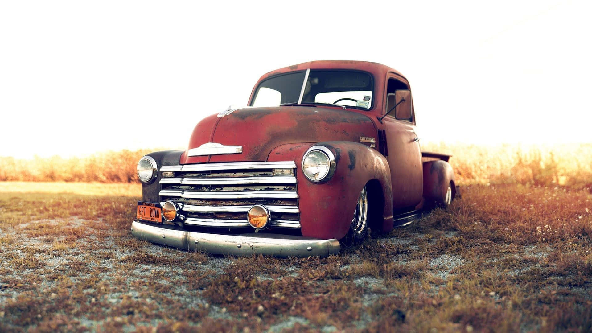 An Old Red Truck Is Parked In A Field