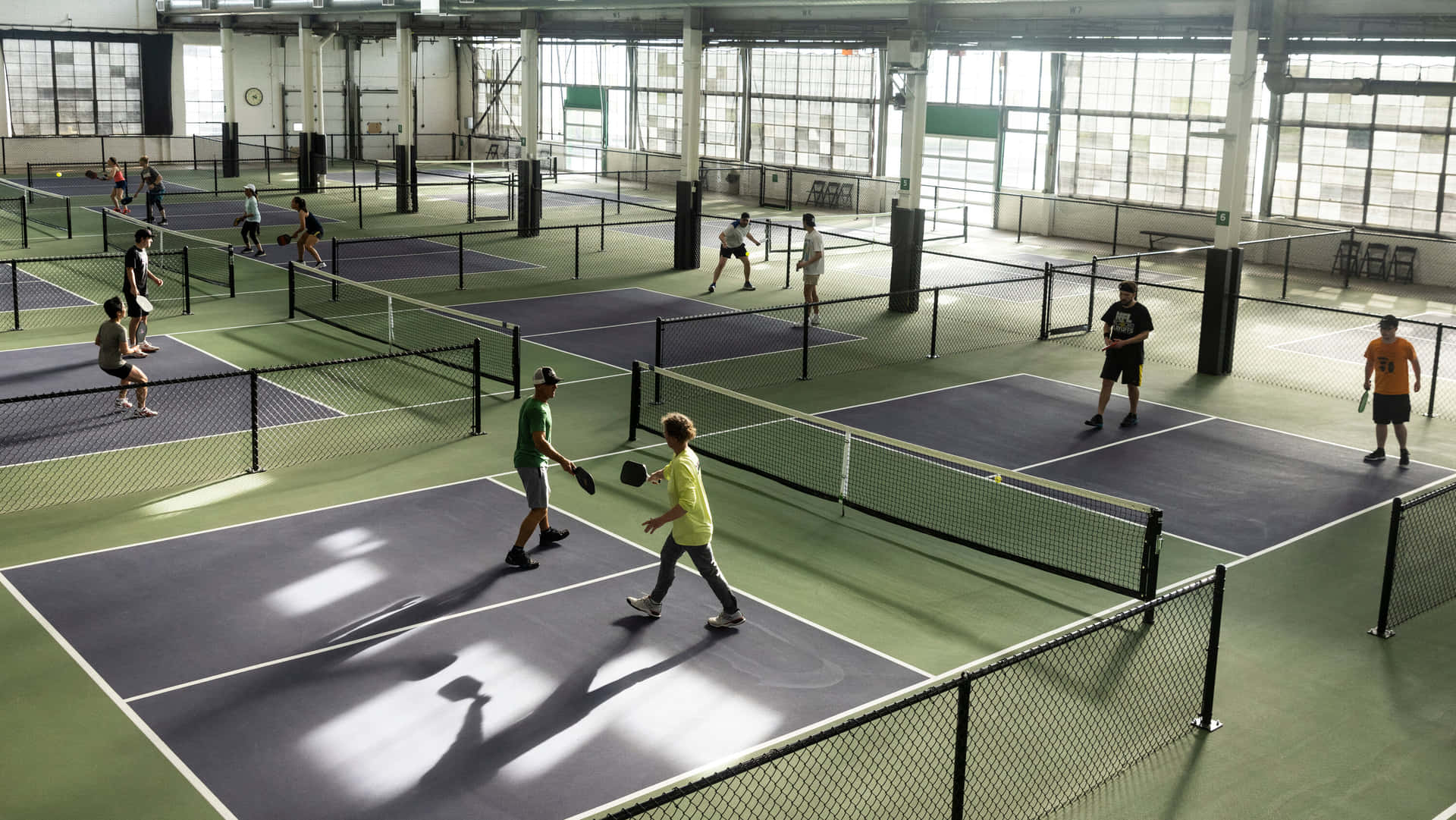 A Group Of People Playing Tennis In An Indoor Court