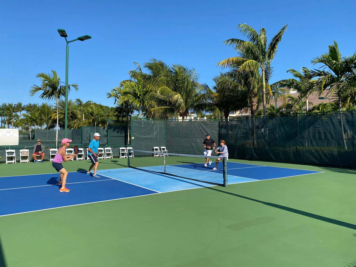 A Group Of People Playing Tennis On A Tennis Court