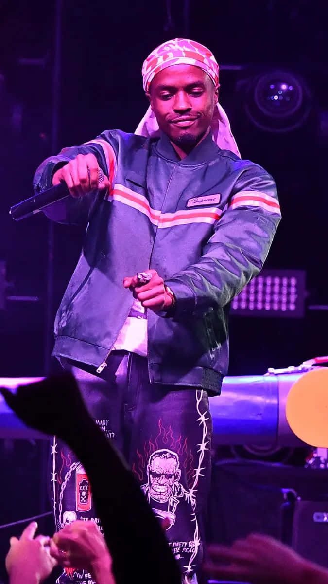 A Man In A Green Jacket Standing On Stage Wallpaper