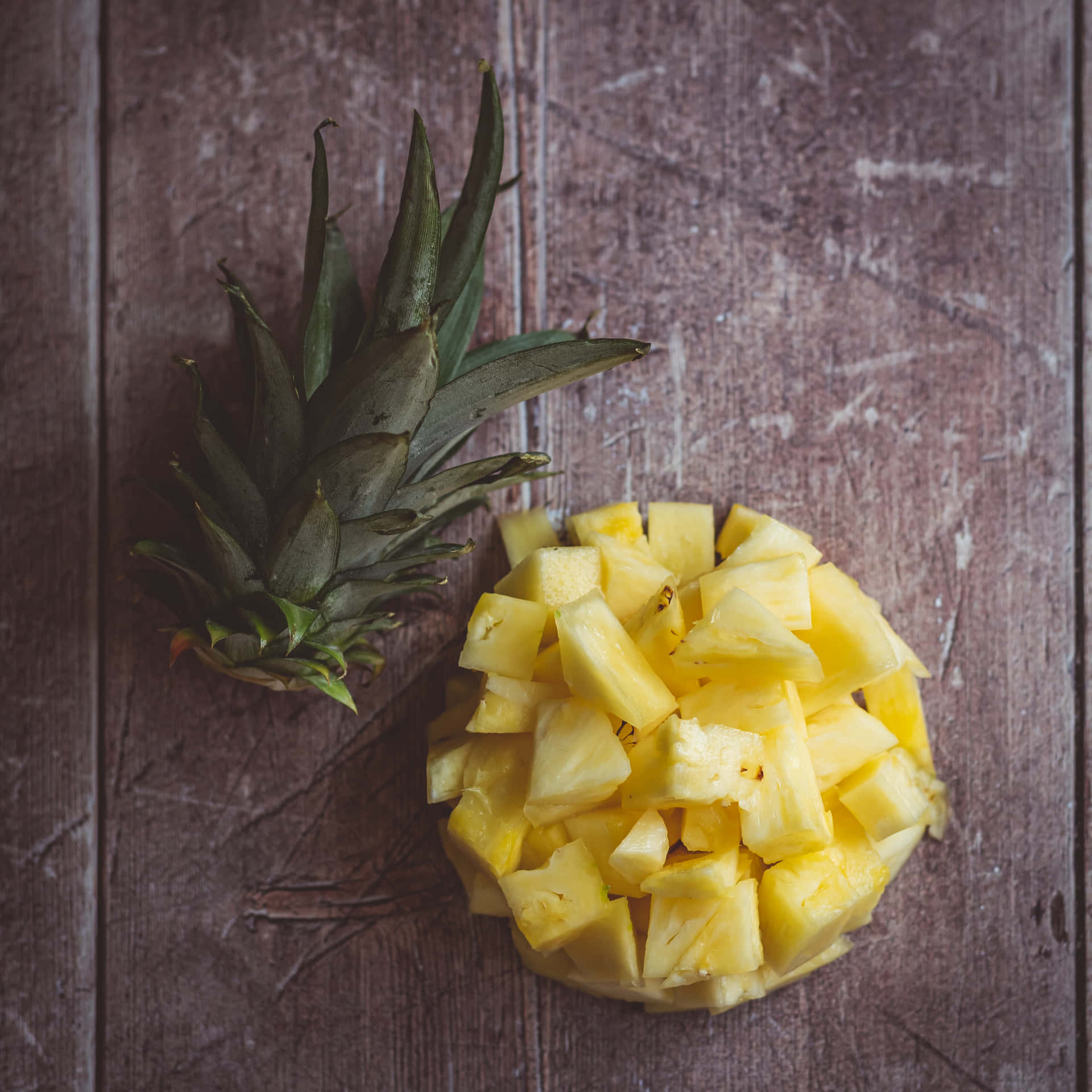 A ripe, golden pineapple set against a white, wooden background.