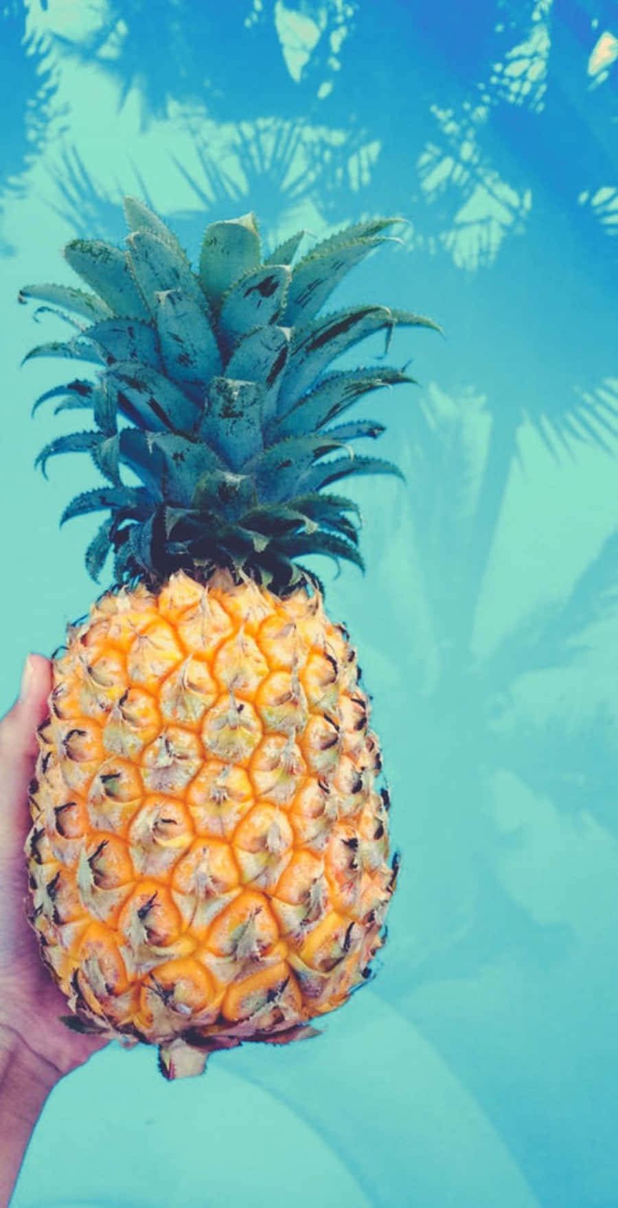 A Person Holding A Pineapple In Front Of A Pool