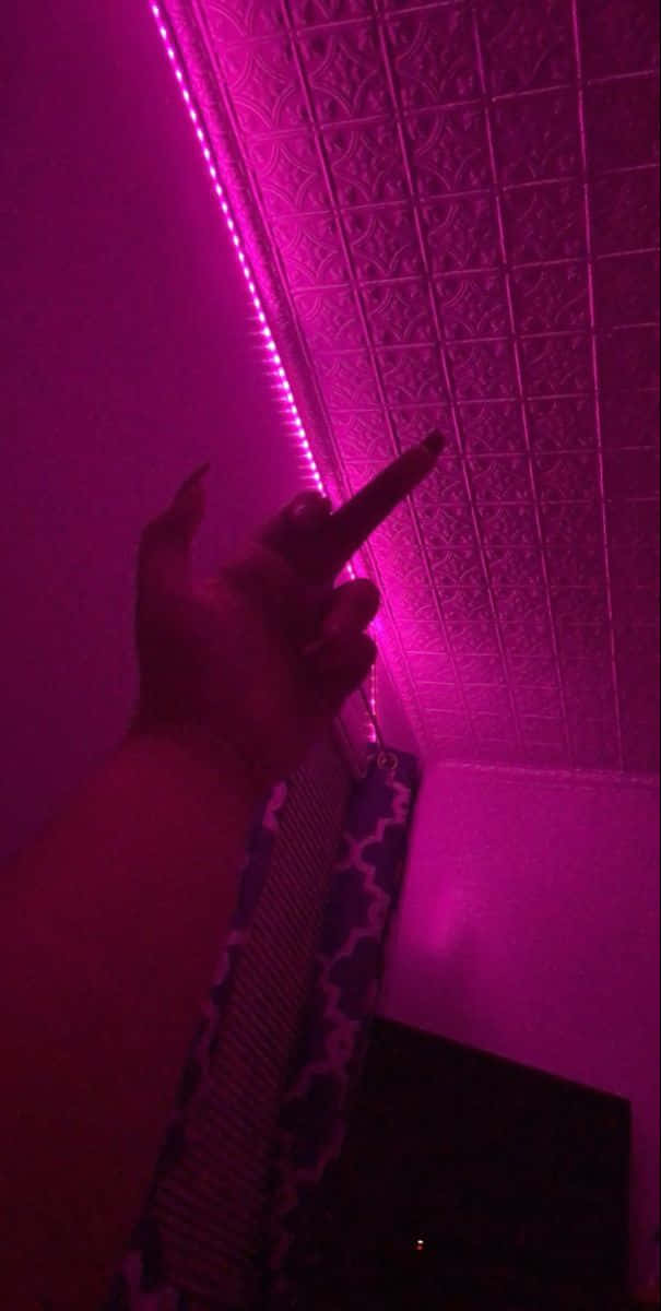 En person holder et pink LED-lys op i mørket. Wallpaper