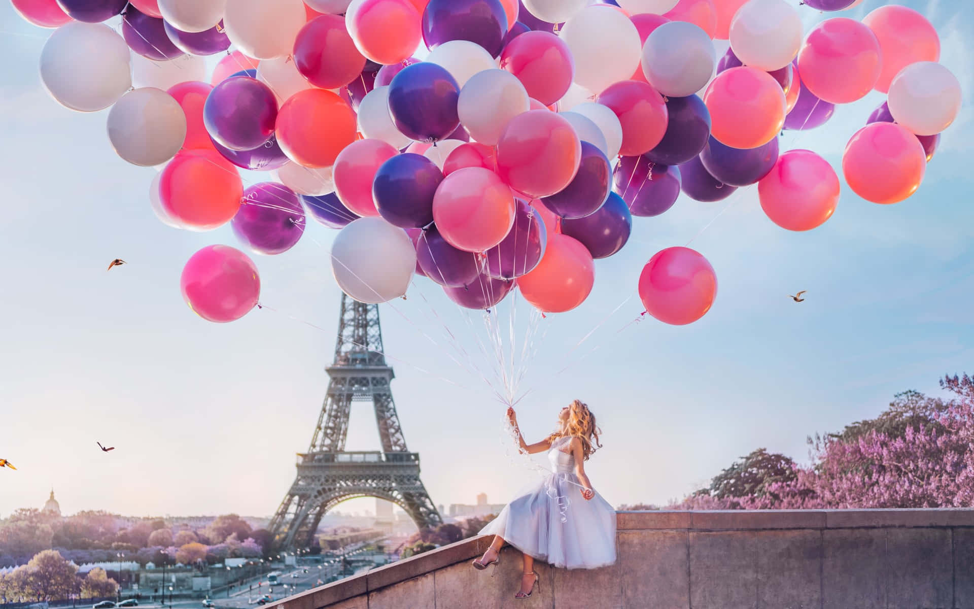 A Woman Is Holding Balloons In Front Of The Eiffel Tower