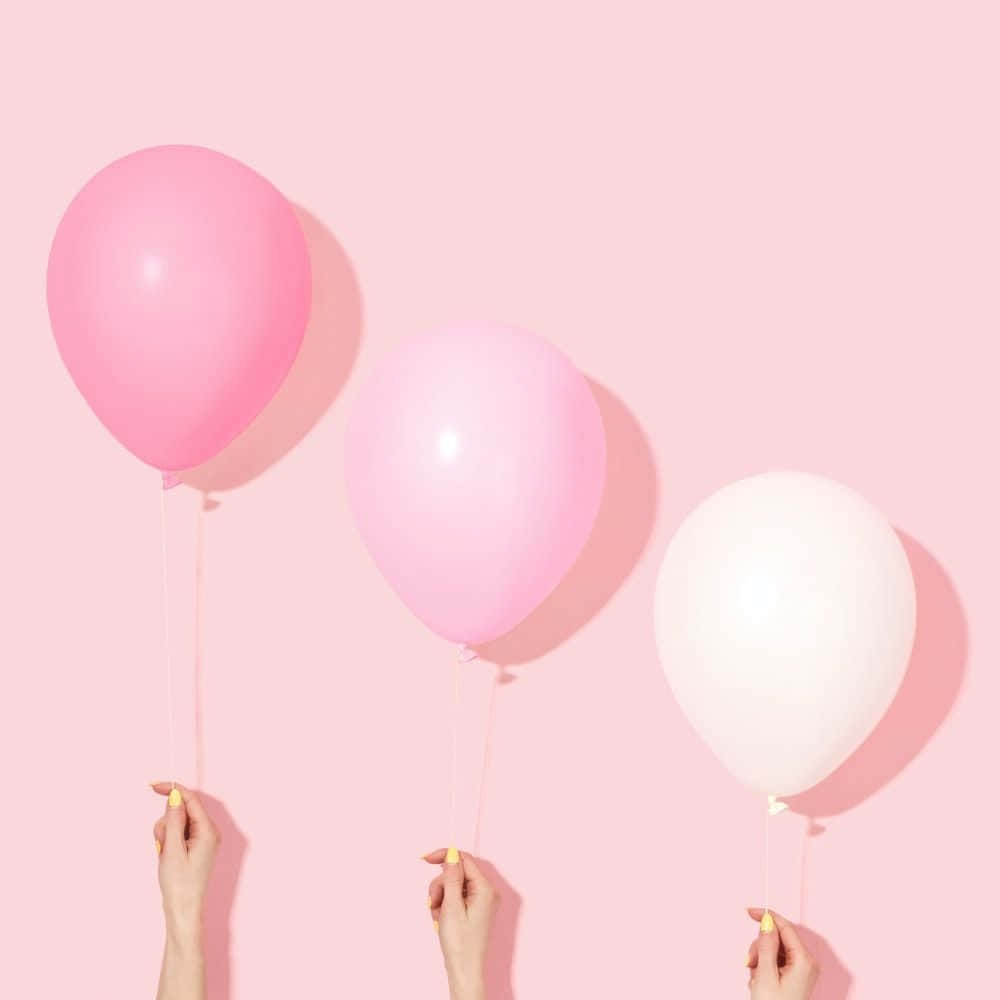 Three Pink And White Balloons In Hands