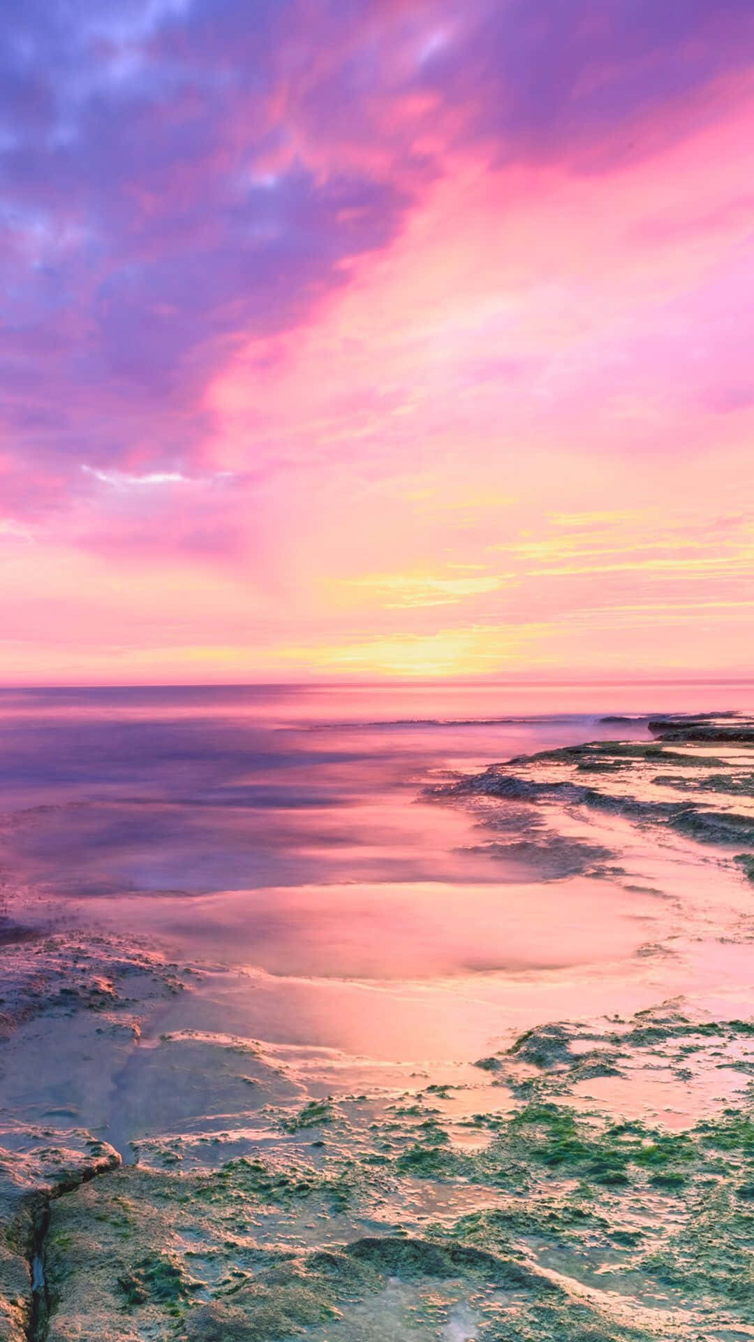 A Pink And Purple Sunset Over The Ocean Wallpaper