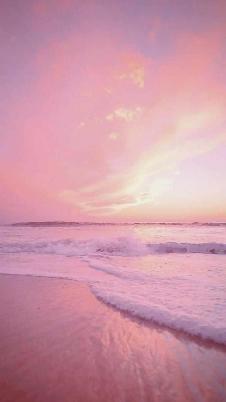 A Pink Sunset On A Beach With Waves Wallpaper
