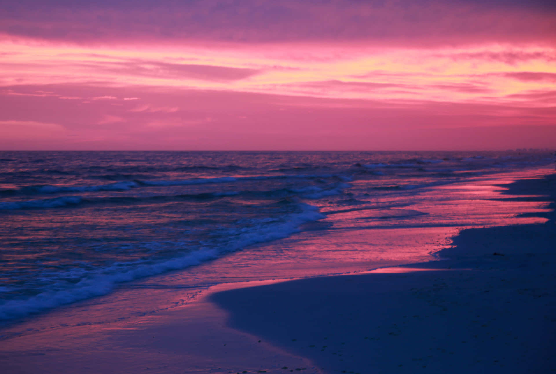 Et billedskønt pastelrosa strand solnedgang, med solstråler strækker sig ud over horisonten. Wallpaper