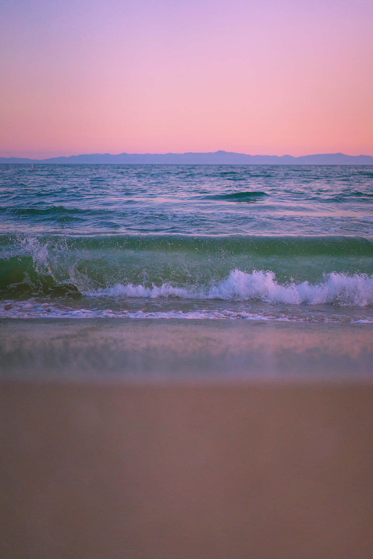 En smuk lyserød solnedgang over stranden Wallpaper