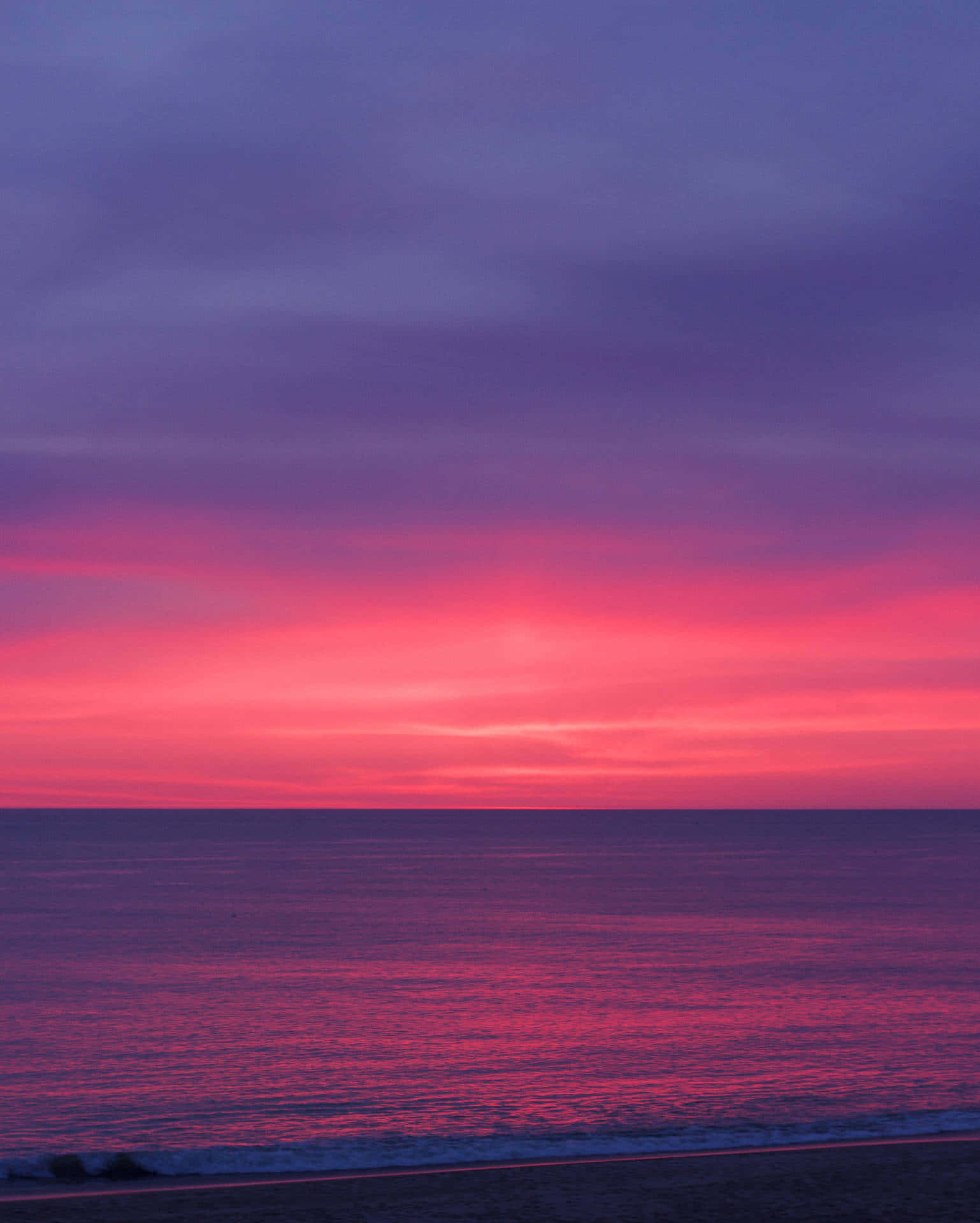 Feel the warmth of the setting sun on a beautiful pink beach Wallpaper