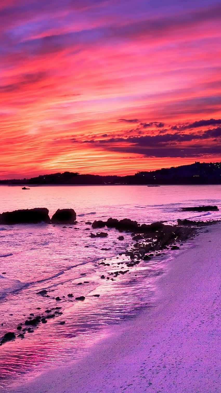 Genießeden Traumhaften Rosa Sonnenuntergang, Während Die Wellen An Deinen Füßen Plätschern. Wallpaper
