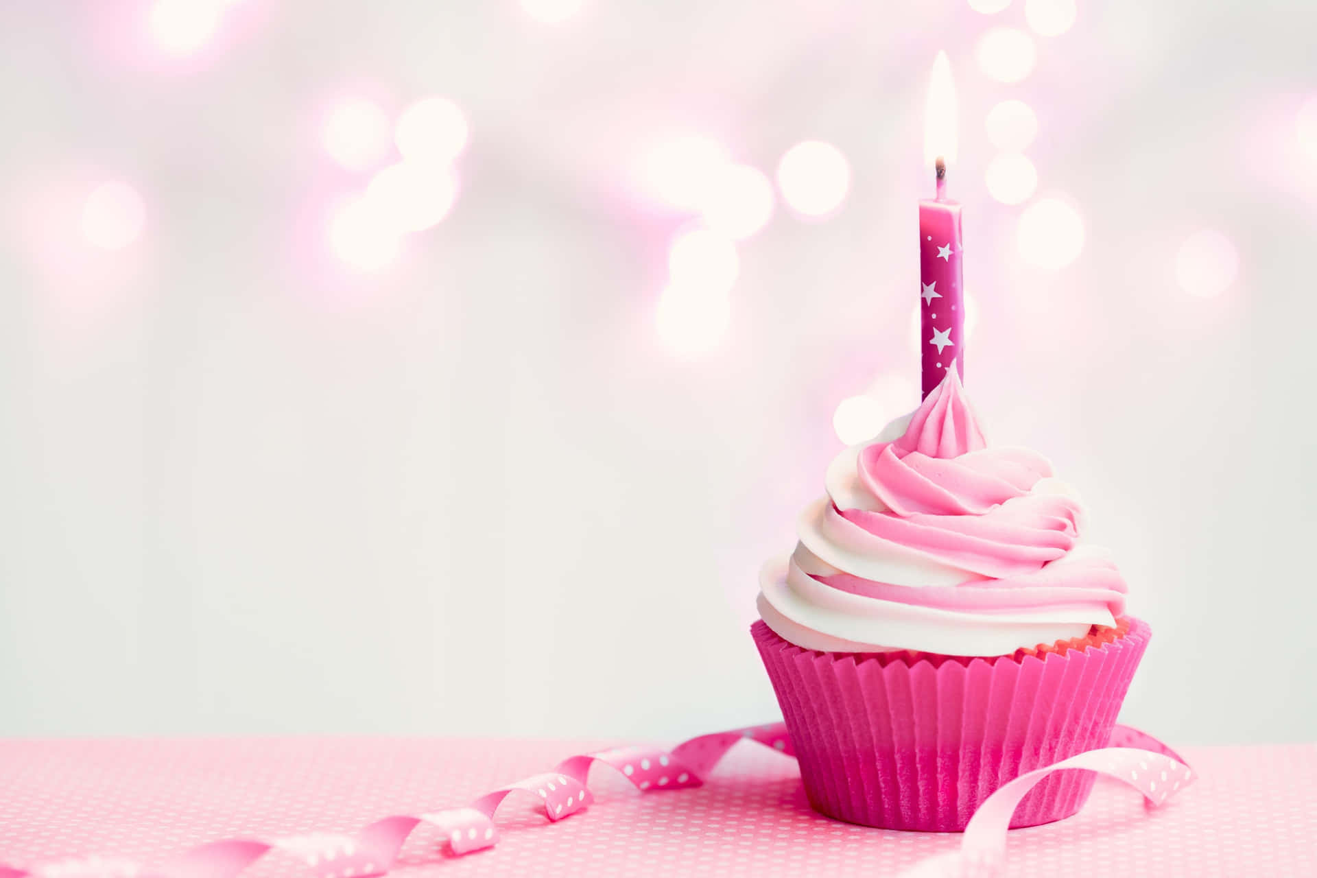 A Pink Cupcake With A Candle On Top Wallpaper