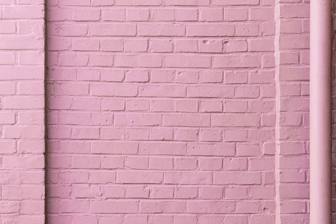 A Pink Brick Wall With A Pipe And A Pipe
