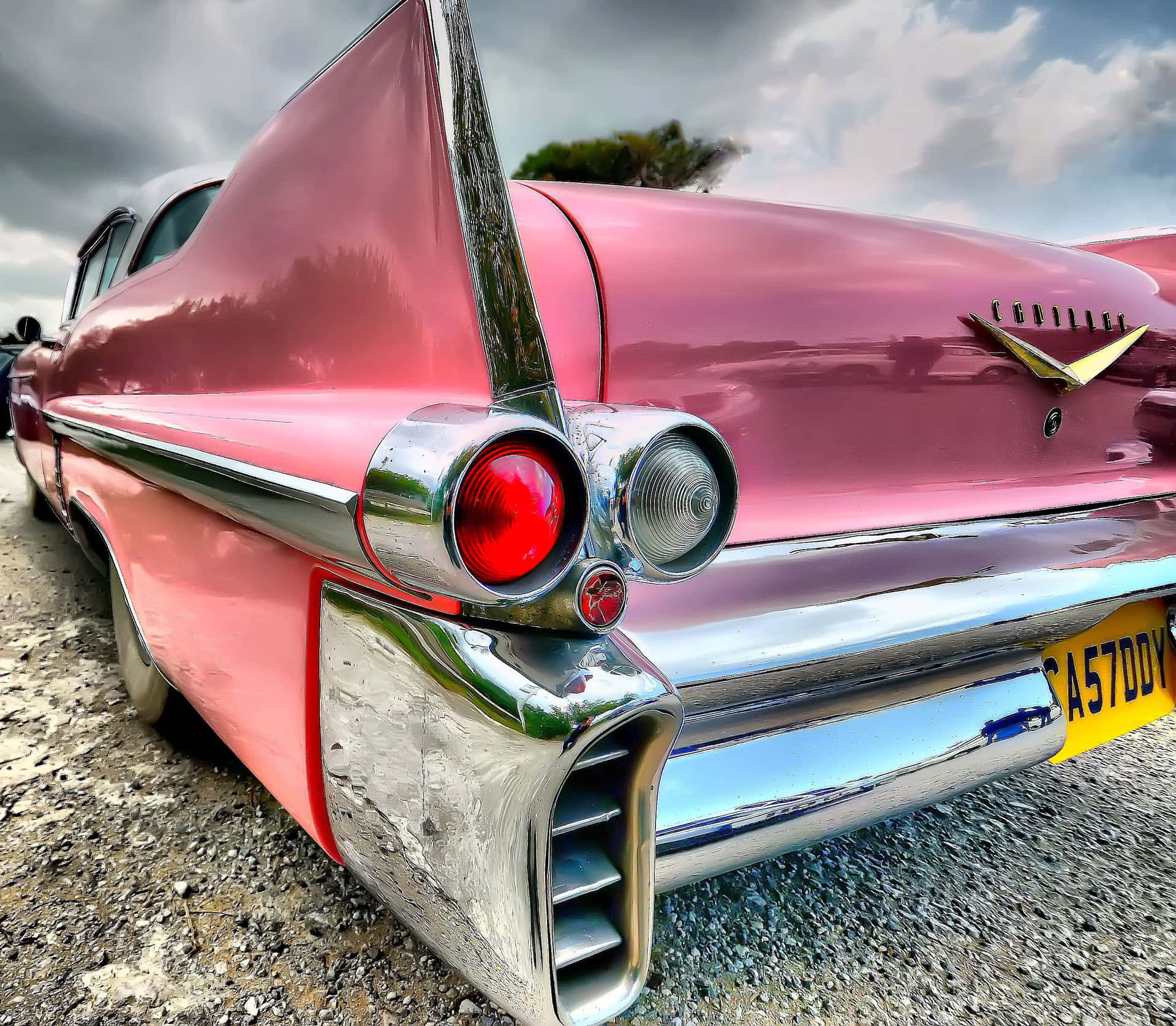 Vintage Pink Cadillac parked under palm trees Wallpaper