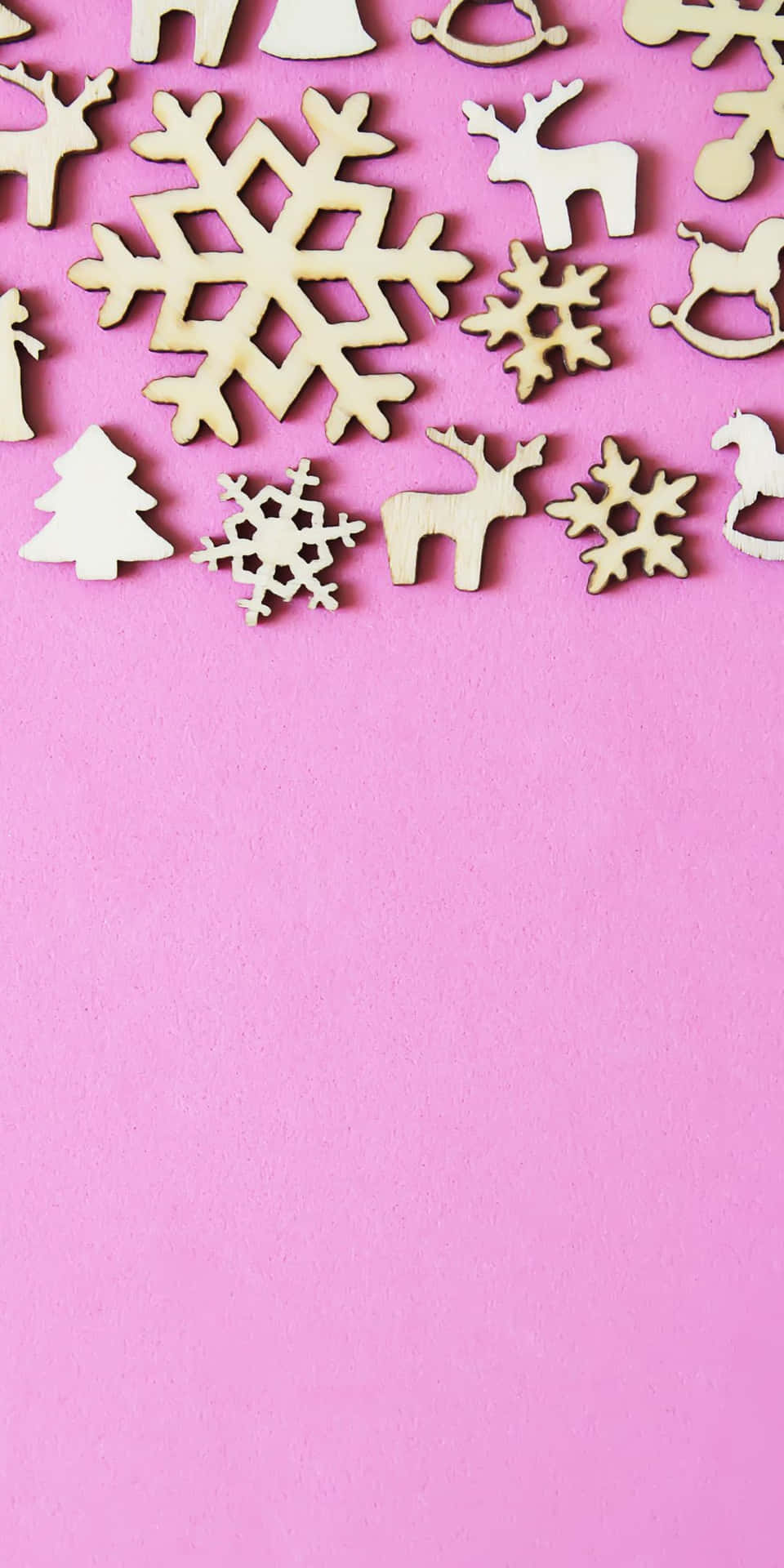A Pink Background With Wooden Christmas Decorations