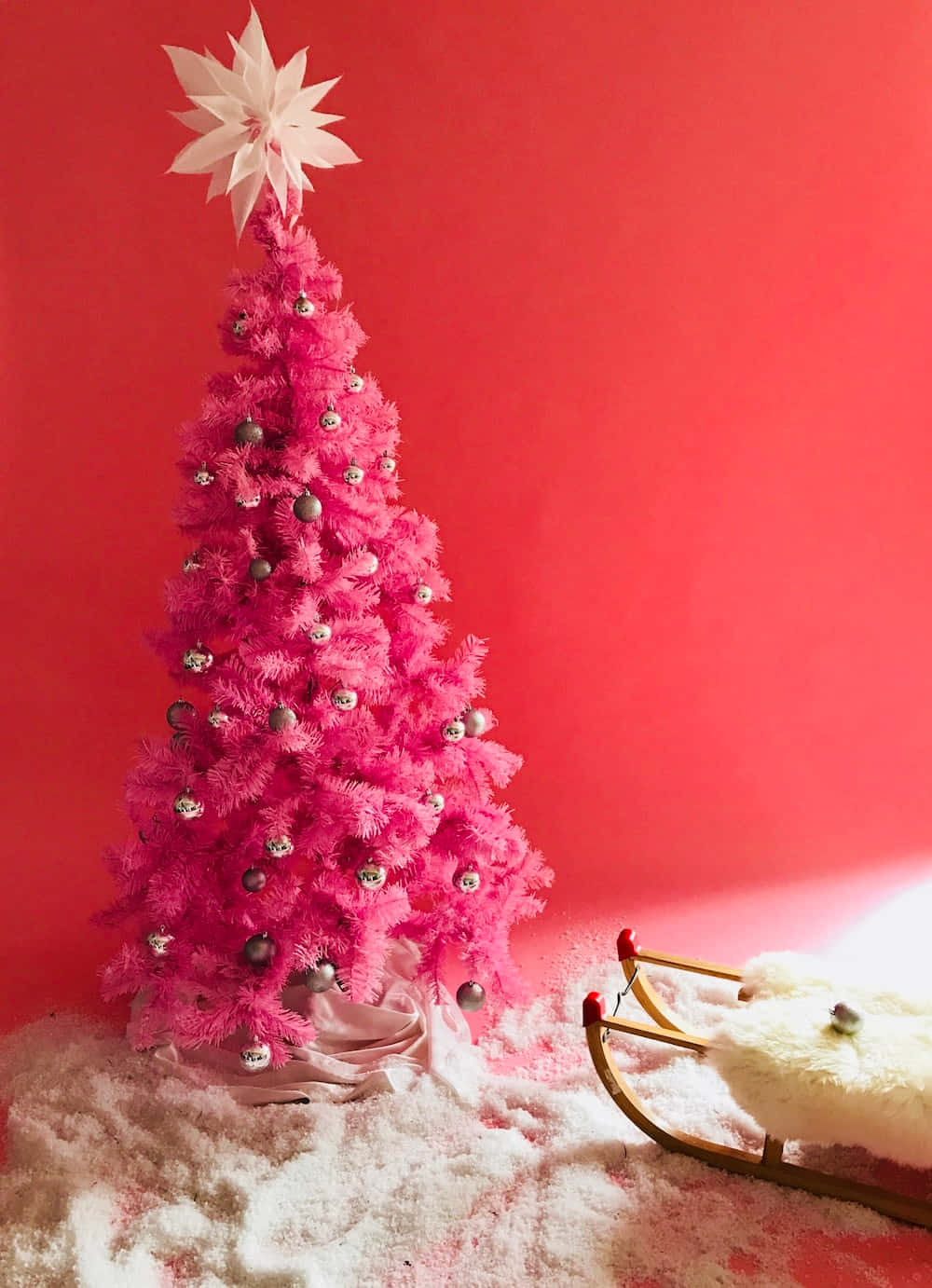 A Pink Christmas Tree With A Sled And Silver Ornaments Wallpaper