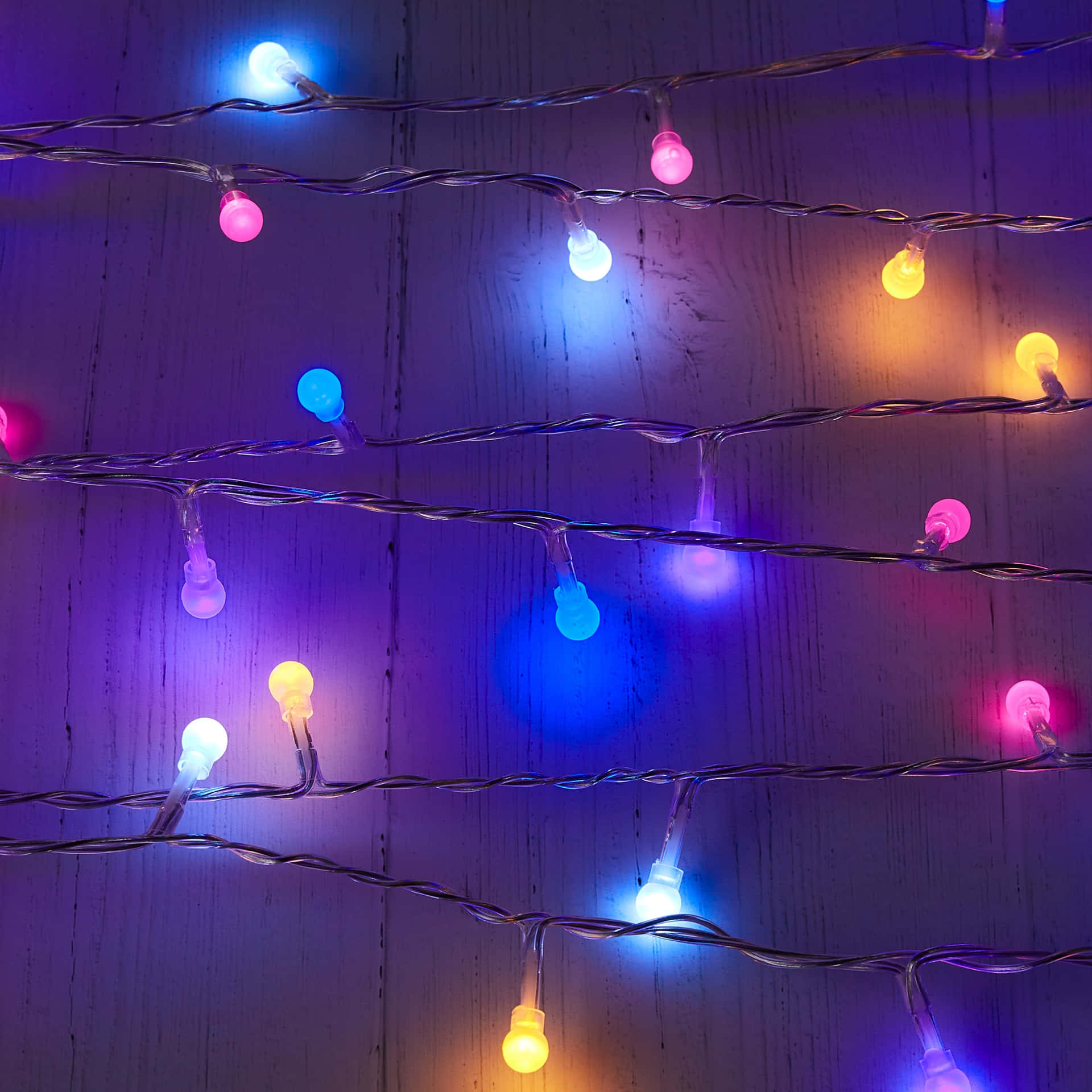 A String Of Multi Colored Lights On A Wooden Surface Wallpaper