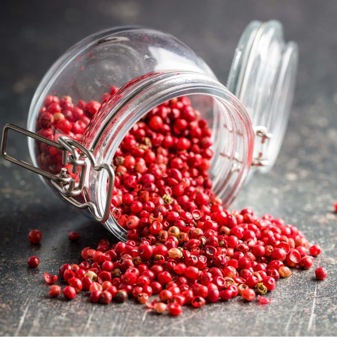A close-up view of vibrant pink peppercorns on a wooden surface. Wallpaper