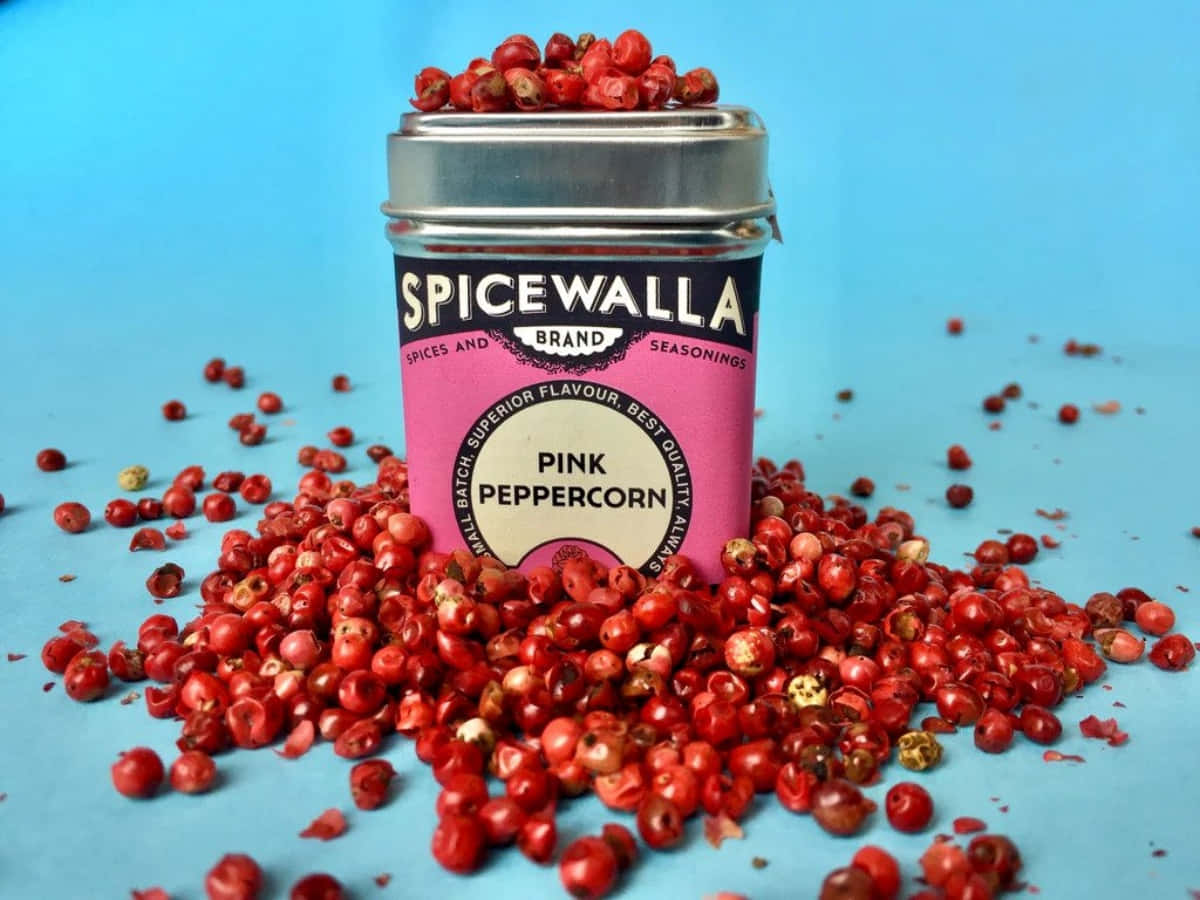 A collection of pink peppercorns on a wooden surface Wallpaper