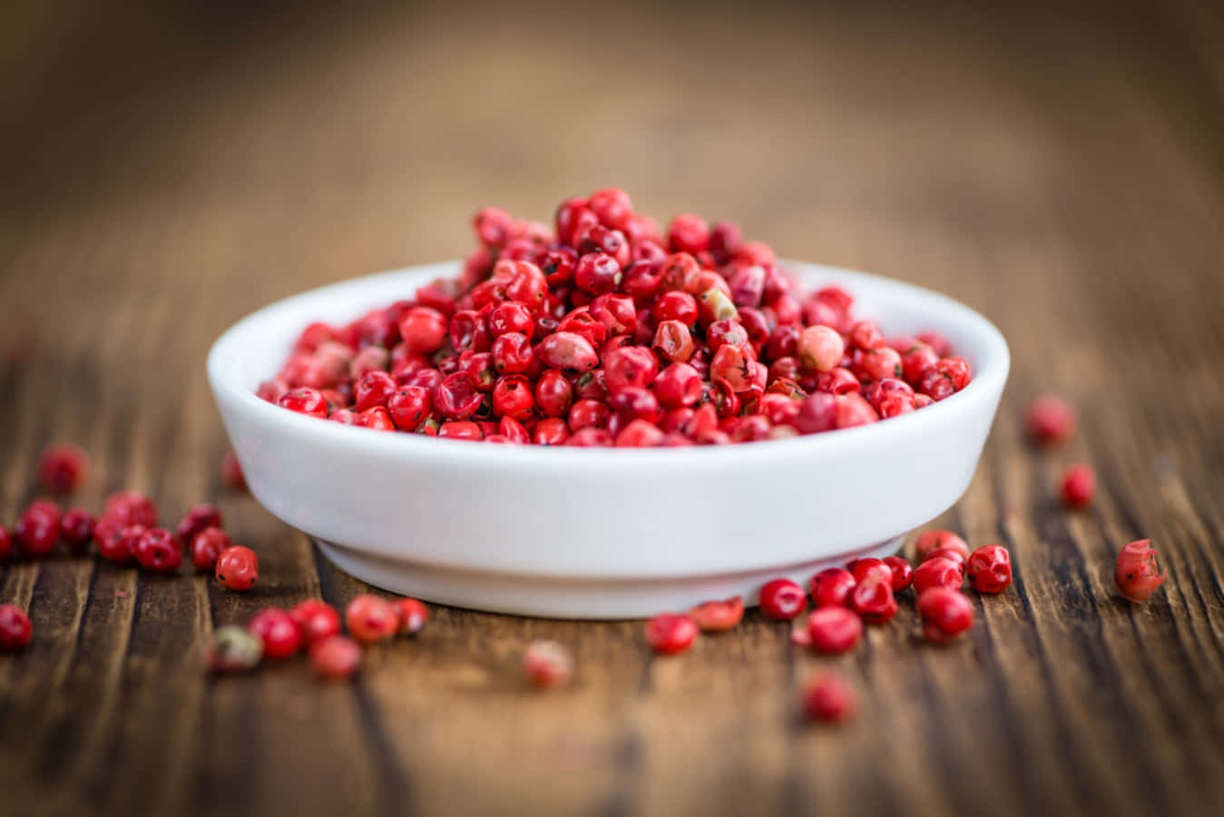 A close-up of pink peppercorns on a wooden surface Wallpaper