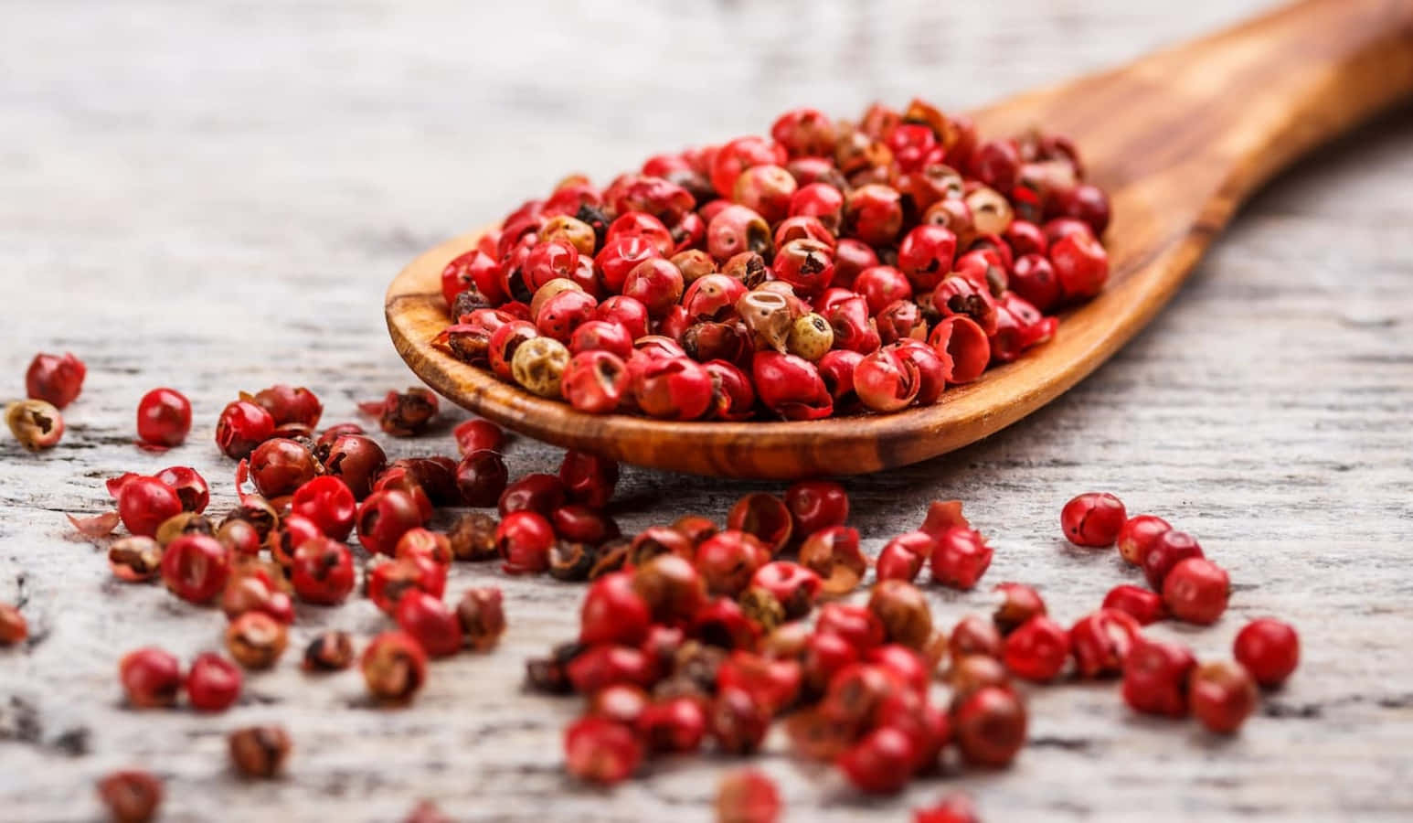 A close-up view of pink peppercorns on a wooden surface Wallpaper