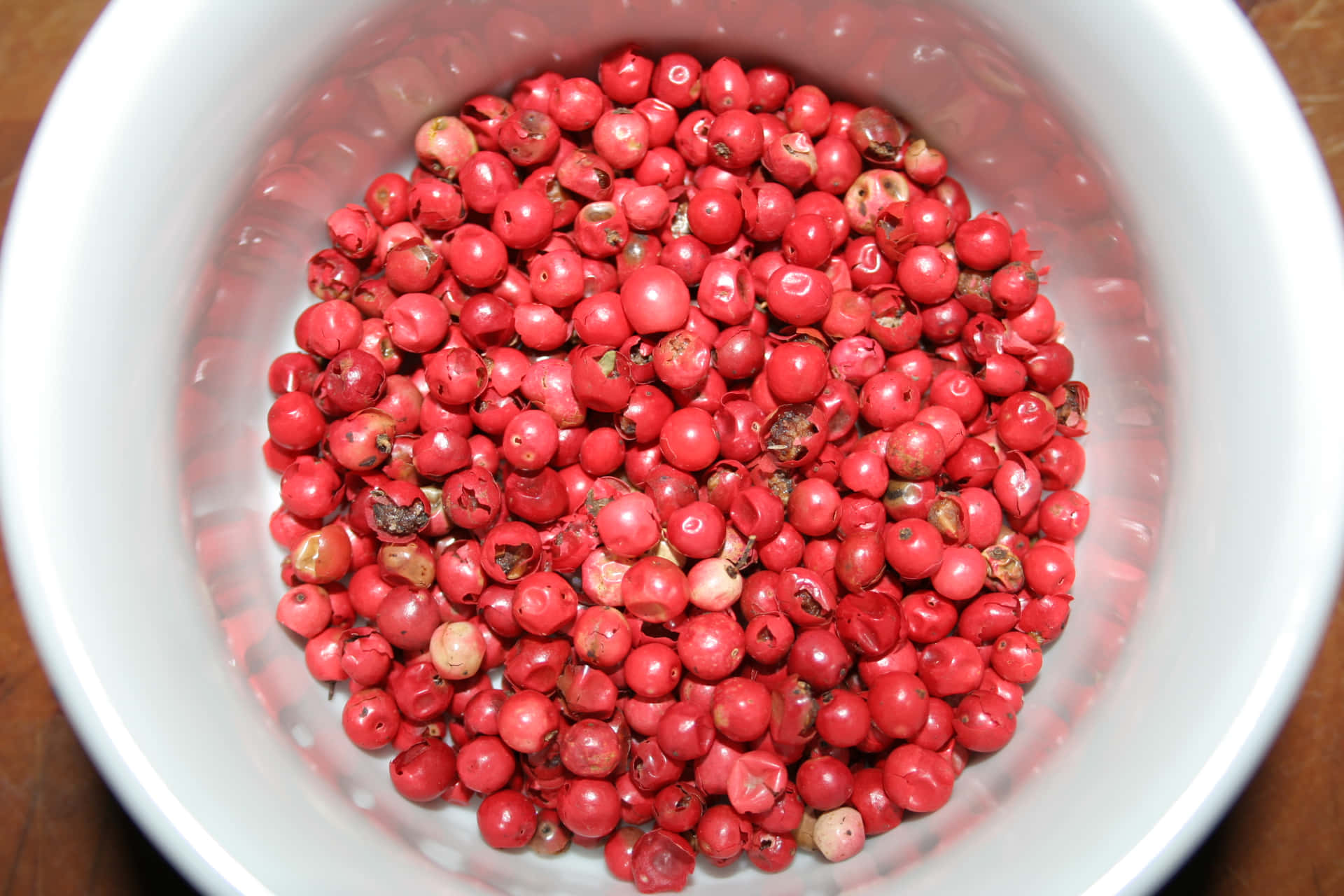 A pile of Pink Peppercorn on a wooden background Wallpaper